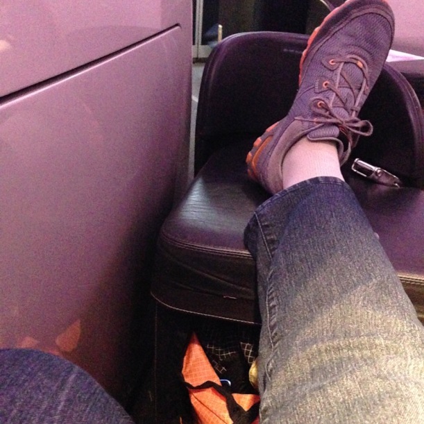 Foot resting on ottoman in Business Class plane cabin