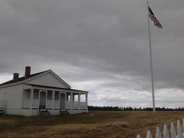 US flag flying against cloudy sky over old building