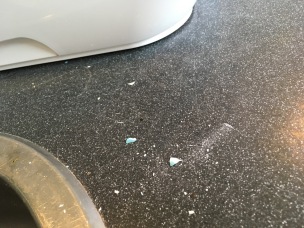 shards of broken, white ceramic sprinkled on black kitchen countertop
