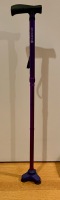 Purple aluminum HurryCane walking stick freestanding on a wood floor